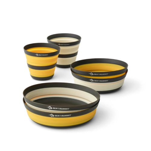 El juego de cocina Frontier de 6 piezas de Sea to Summit incluye vajilla plegable en varios tamaños de tazones y tazas. Los artículos son de color amarillo con bordes negros y grises, y están hechos de material flexible que permite compactarlos para guardarlos y transportarlos fácilmente.