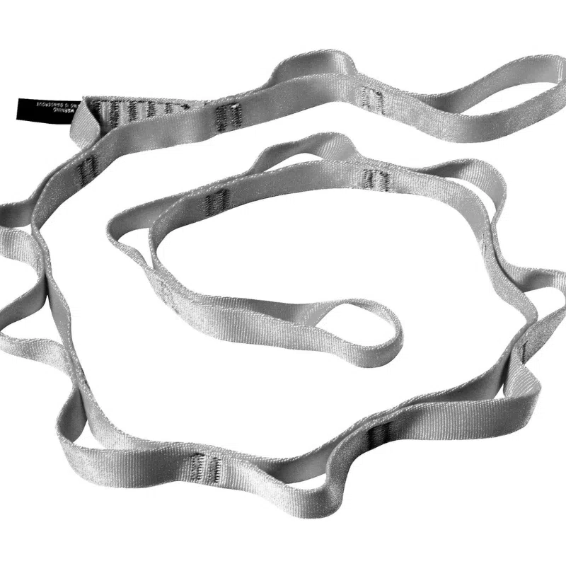 La eslinga de escalada Cinta Black Diamond de nailon de 18 mm con cadena tipo margarita, con múltiples presillas, está enrollada de forma suelta. Fabricada con tejido de nailon duradero de 18 mm, es ideal para asegurar a los escaladores o el equipo durante los ascensos. La eslinga, muy utilizada, muestra costuras visibles y una etiqueta en un extremo.