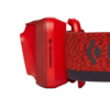 Vista lateral de una linterna frontal de Black Diamond de color rojo con un ícono USB y la palabra "RECARGABLE" impresa en el costado. Cuenta con una banda elástica estampada.