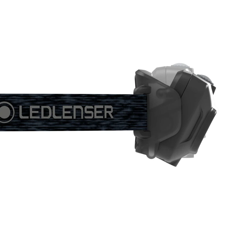 Una linterna frontal LED Lenser HF4R Core 500lm compacta y robusta en color negro y gris con una correa "LEDLENSER" ajustable se coloca a la derecha, resaltando su elegante diseño.