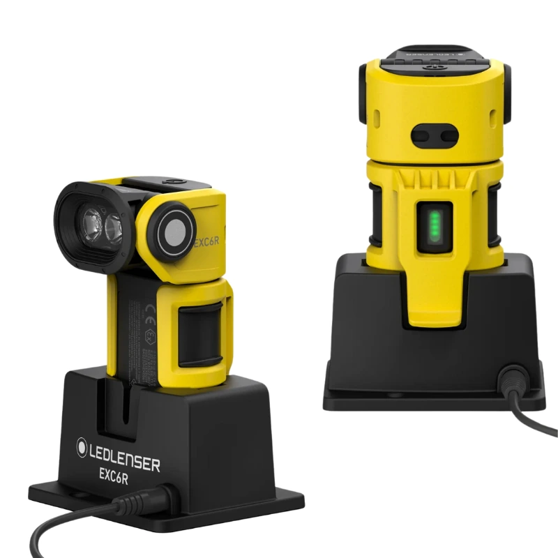 Dos linternas Linterna Recargable Led Lenser EXC6R Atex 300lm, en color amarillo y negro, se presentan sobre una base de carga negra conectadas mediante un cable. En su diseño destacan dos piezas cilíndricas con lentes y botones visibles, enfatizando su seguridad con certificación Atex.