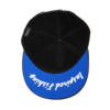 La Gorra Okuma Motif Flat PA01C022K es una gorra de béisbol azul con una parte inferior negra, vista desde abajo, y muestra "Inspired Thinking" en cursiva blanca en el ala.