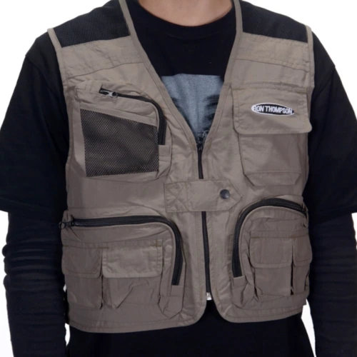 Con el chaleco de pesca Ron Thompson Mesh Lite, esta persona luce un chaleco táctico gris con múltiples bolsillos con cierre y un parche prominente, combinado con una camisa negra de manga larga debajo.
