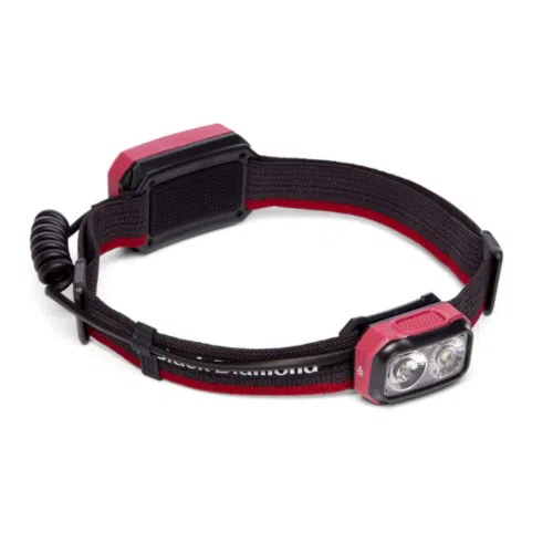 Presentamos la linterna frontal Black Diamond Onsight 375, una linterna frontal roja y negra con una unidad de luz rectangular que tiene dos lentes circulares. Cuenta con una correa elástica ajustable y una batería trasera, lo que la hace ideal para iluminación con manos libres durante diversas actividades.
