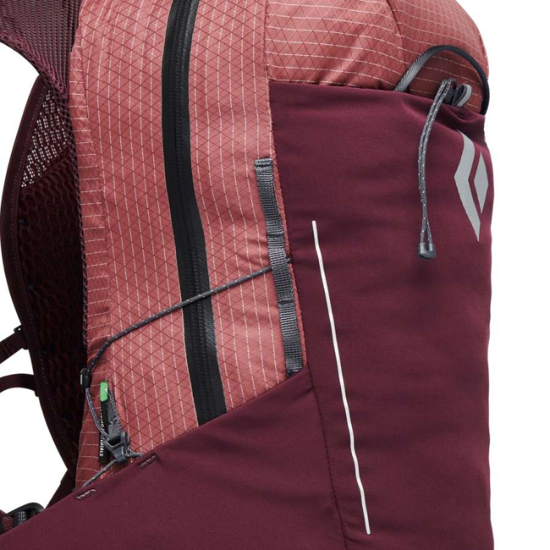 Primer plano de la mochila Black Diamond Pursuit de 15 l en cerezo y azul tinta, que presenta un compartimento con cierre, una línea decorativa blanca y un pequeño logotipo. El material presenta un patrón texturizado en forma de cuadrícula y un bolsillo de malla parcialmente visible en el lateral.
