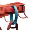 Primer plano de un arnés de escalada rojo, similar al arnés de escalada Black Diamond Momentum Mujer, con trabillas azules y rojas. Este arnés de escalada presenta una hebilla segura y costuras visibles, diseñadas para garantizar la seguridad durante las actividades de escalada. El foco está en las trabillas y la hebilla, detalladas con gran detalle.