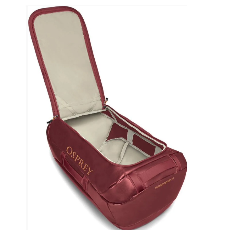 El bolso de transporte Osprey Duffel 95 en color rojo se abre por completo para mostrar un interior espacioso forrado con tela gris claro. Sus diversos compartimentos brindan una organización conveniente y el nombre de la marca "Osprey" se destaca de manera destacada en el costado.