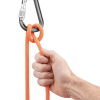 Una mano agarra una cuerda de escalada naranja atada en un nudo seguro a un Mosquetón Seguridad Petzl Attache Bar, demostrando una configuración de escalada segura y confiable.