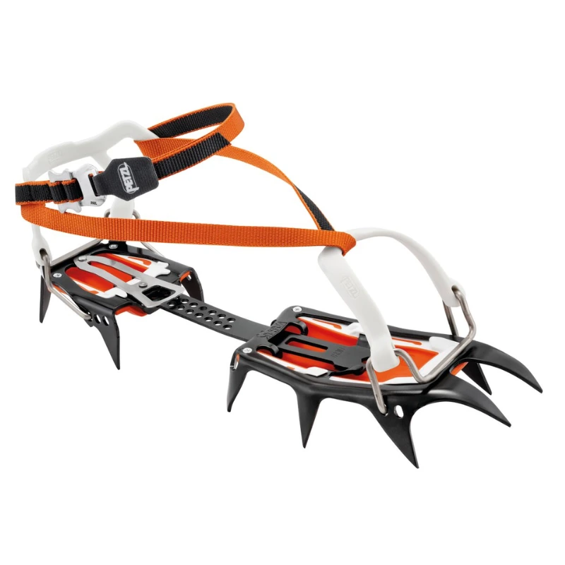 Los crampones de alpinismo Petzl Vasak, unos crampones metálicos para escalada en hielo con puntas negras afiladas, presentan fijaciones de plástico de color naranja y blanco y una correa ajustable, lo que garantiza una pisada segura en terrenos helados sobre un fondo liso.
