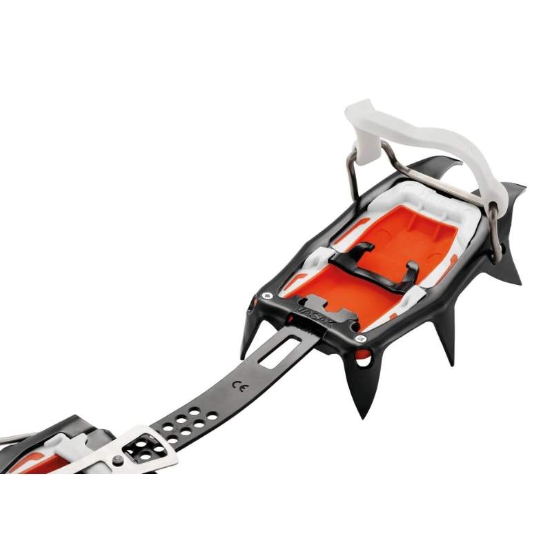 Primer plano de los crampones de alpinismo Petzl Vasak, en el que se destaca su diseño en negro, naranja y blanco con clavos de metal y correas ajustables. Perfectos para terrenos helados, estos crampones ofrecen un armazón resistente y puntos de sujeción fiables para una tracción óptima.