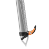 Primer plano de un piolet plateado para montañismo con el modelo Petzl Trigrest. Tiene una empuñadura de goma negra y naranja, una punta de metal puntiaguda en la parte inferior y ranuras horizontales en el mango para un mejor agarre.