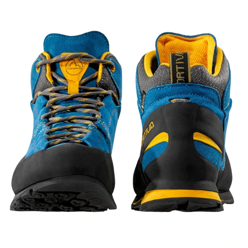 Las zapatillas de senderismo La Sportiva Boulder X Mid GTX en azul y amarillo, con suelas de goma negras y detalles en gris, se muestran en las vistas frontal y posterior. El diseño estructurado es perfecto para aventuras al aire libre, y los cordones y las costuras realzan sus colores vibrantes.