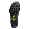 La imagen muestra la suela de una bota de senderismo negra como la Zapatilla de Aproximación La Sportiva TX4 Mujer, con tacos hexagonales e irregulares para mayor tracción. Un pequeño logotipo amarillo de Vibram se destaca cerca del centro sobre un fondo blanco liso.