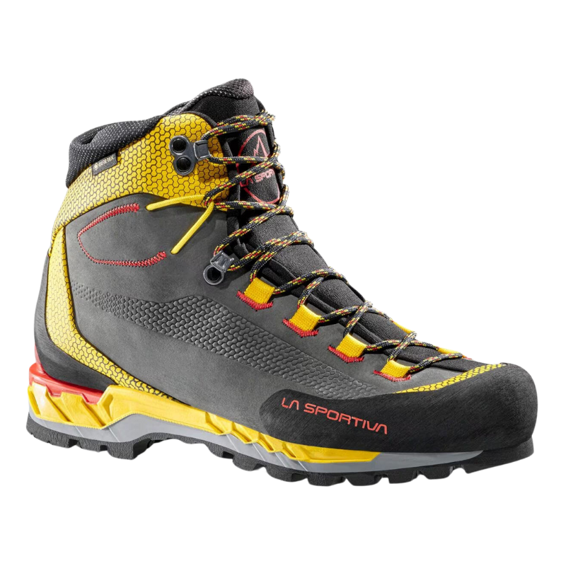 La Sportiva Trango Tech Leather GTX es una bota de senderismo resistente que presenta una combinación de colores gris y amarillo llamativos con detalles en rojo, suela texturizada, soporte alto para el tobillo y cordones intrincados. La marca "La Sportiva" se muestra de forma destacada en el lateral.