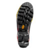 La imagen muestra la suela de una zapatilla negra, concretamente la Bota de Montaña La Sportiva Aequilibrium LT GTX, con un dibujo de banda de rodadura resistente y multidireccional. Presenta detalles en amarillo y rojo, y el nombre de la marca es visible en una pequeña sección amarilla.
