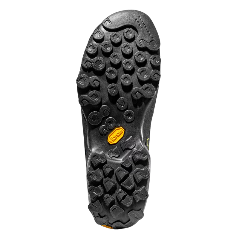 La suela de goma negra de La Sportiva TX4 Mid GTX presenta dibujos redondos y geométricos para un excelente agarre. Un logotipo naranja en el centro resalta su diseño, asegurando una tracción confiable en superficies irregulares.