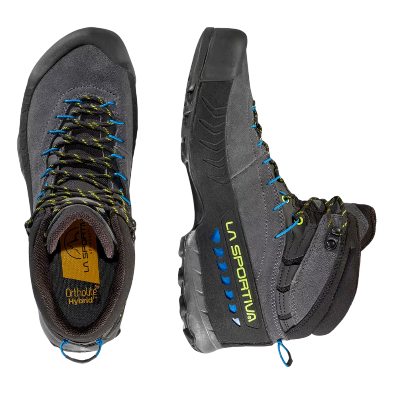 Un par de botas de senderismo La Sportiva TX4 Mid GTX, que se muestran de arriba a abajo, son de color gris oscuro con cordones y detalles en azul y tienen una suela resistente para uso en exteriores. Tienen una etiqueta "Ortholite Hybrid" en el interior.