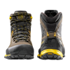 Un par de botas de senderismo marrones y amarillas con detalles en negro, similares a las La Sportiva TX5 GTX, presentan una vista frontal y posterior. El diseño incluye materiales duraderos, cordones intrincados, un cuello acolchado en el tobillo y una suela robusta ideal para actividades al aire libre.