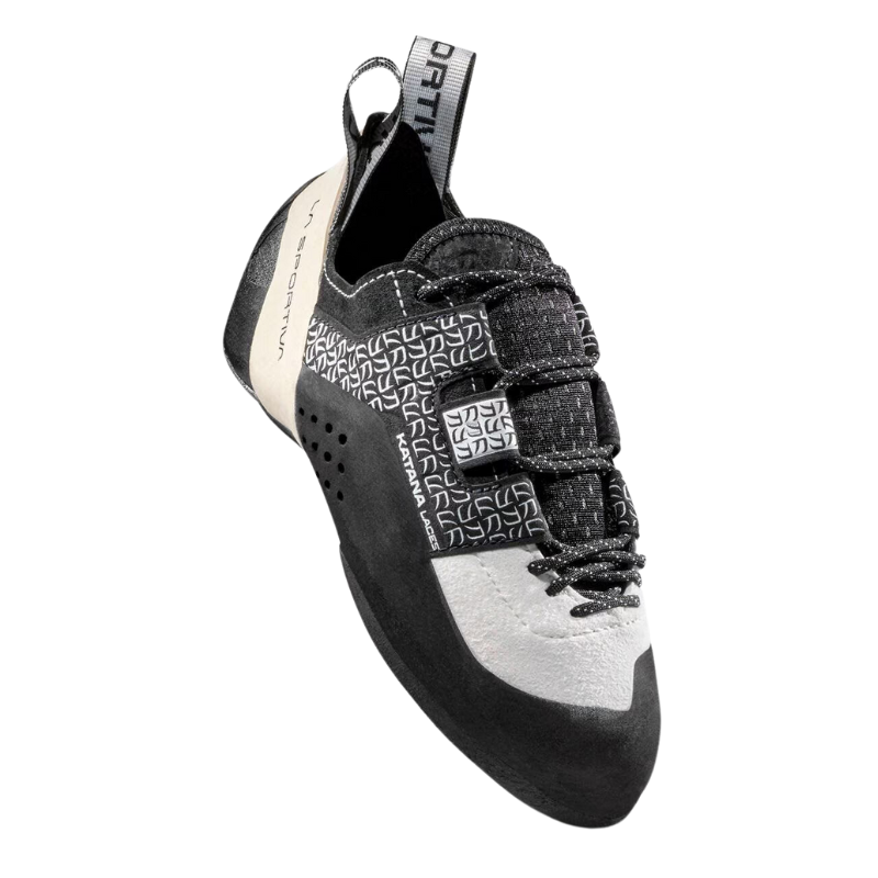 El modelo La Sportiva Katana Laces para mujer es un calzado de escalada en blanco y negro que presenta correas de velcro, un patrón geométrico en la parte superior, tirador en el talón y logotipo en la lengüeta. Su diseño elegante es perfecto para actividades de escalada.