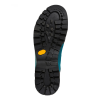 La imagen resalta la suela resistente de la zapatilla de trekking La Sportiva Trango Trk GTX, con una banda de rodadura negra con ranuras y tacos profundos para una mejor tracción en terrenos variados. Un hexágono amarillo se encuentra cerca del centro y el cuerpo de la bota es azul.