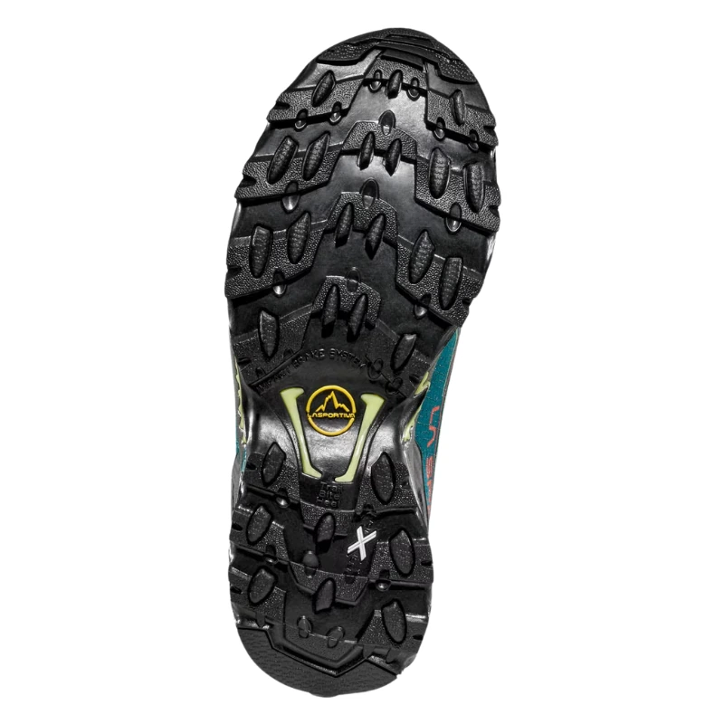 Primer plano de la suela de la zapatilla de trekking para mujer La Sportiva Ultra Raptor II Mid GTX, que muestra un patrón resistente y texturizado con surcos profundos y diseños de banda de rodadura variados. El logotipo aparece en el centro, entre líneas contorneadas y colores vibrantes, lo que resalta su enfoque en el agarre y la durabilidad.