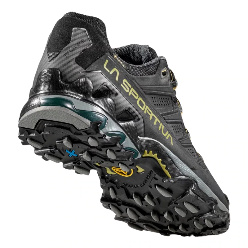Descubre las zapatillas de montaña La Sportiva Ultra Raptor II Leather GTX, unas zapatillas de trail running en un resistente color negro y gris. Presentan una banda de rodadura agresiva para un agarre superior y la marca icónica en el lateral.