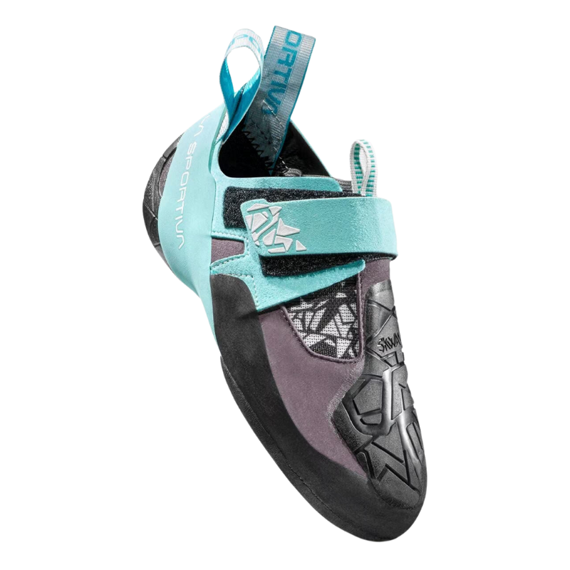 Primer plano de una zapatilla de escalada La Sportiva Skwama Vegan (copia) en verde azulado y negro que resalta la correa de velcro, los patrones geométricos en la puntera y la presilla del talón. La palabra "La Sportiva" se ve en la correa superior y en el costado.