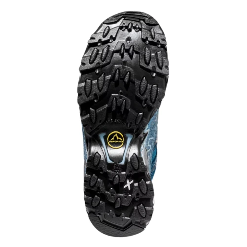 La imagen muestra la suela de La Sportiva Ultra Raptor II Mujer, que destaca un dibujo de banda de rodadura negro y resistente para un agarre superior. Las ranuras y los tacos intrincados se realzan con la marca y los detalles del logotipo en amarillo y blanco en la suela.