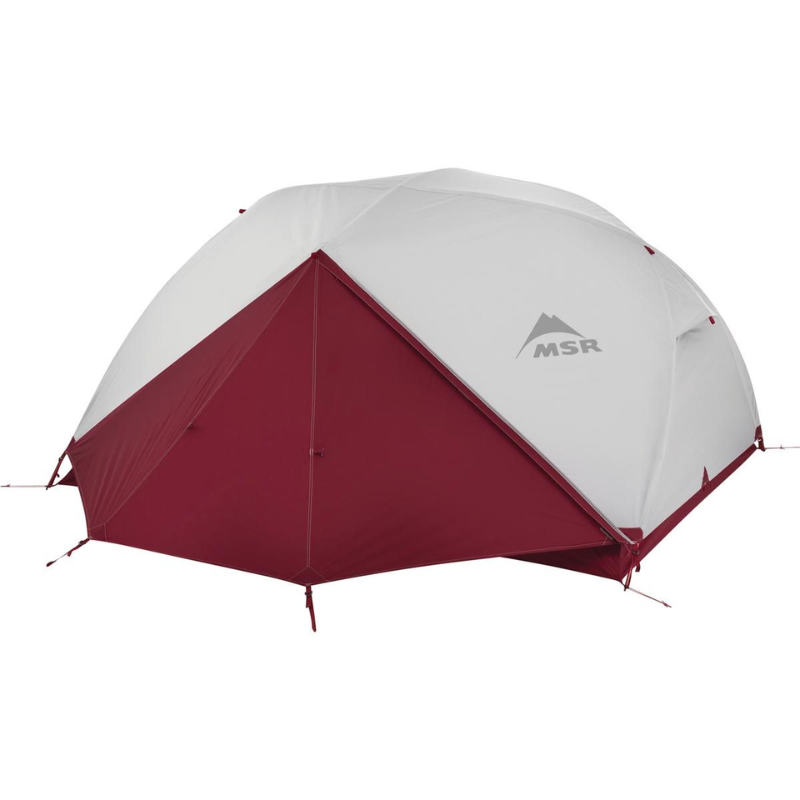 La carpa Carpa MSR Elixir 2 (copia), de color rojo y blanco, con forma de cúpula y el logotipo de MSR en un lateral, está instalada con un toldo sobre una superficie plana.