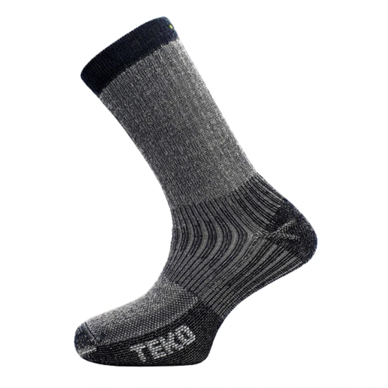 Un calcetín gris y negro con textura acanalada, diseñado para brindar comodidad y durabilidad. Este calcetín Teko cuenta con soporte de amortiguación total junto con áreas reforzadas en el talón y los dedos. La palabra "TEK2" es visible cerca del área de los dedos, perfecto para tus aventuras de eco-senderismo.