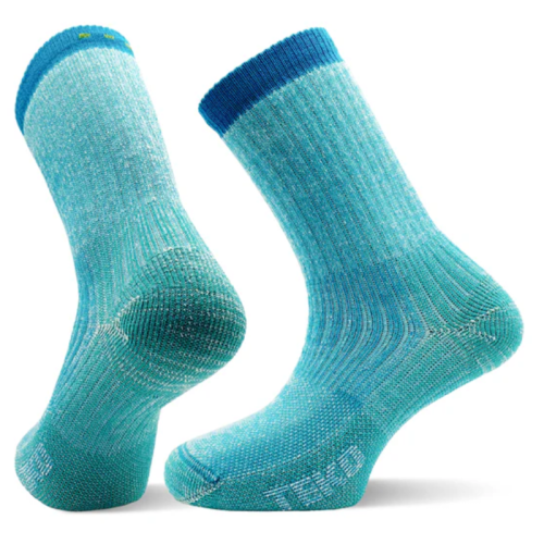Se muestran dos calcetines Calcetín Teko EcoHikong Medium Full Cushion 3.0 en color azul verdoso. La parte inferior del calcetín izquierdo revela una amortiguación gruesa, mientras que el calcetín derecho se mantiene en posición vertical, mostrando su textura acanalada y su puño en azul más oscuro.