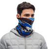 Una persona que viste una chaqueta gris y una bandana estampada azul y negra Buff Original EcoStretch Licencias Valparaíso 2020 que le cubre el cuello y la parte inferior del rostro. Con cabello corto y oscuro, mira hacia un lado, exudando un aire de misterio.