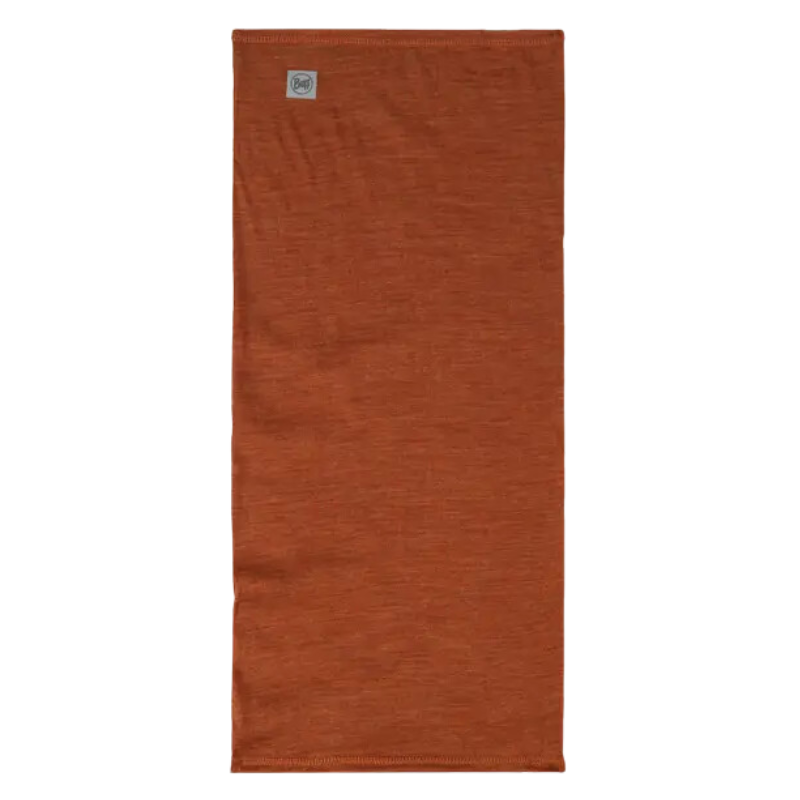 La bandana Buff Merino Lightweight Multistripes Maize presenta un diseño rectangular de color óxido con una pequeña etiqueta en la parte superior izquierda. Se asemeja a una bandana liviana con tela texturizada y bordes prolijamente cosidos.