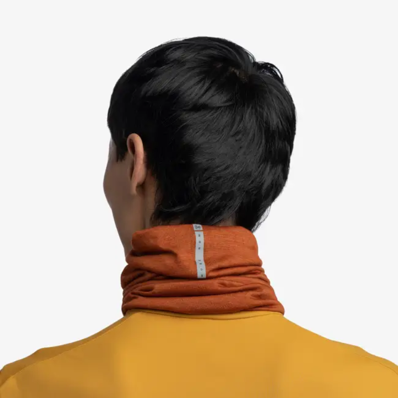 Una persona con cabello corto y negro está de espaldas, vistiendo una camisa color maíz y un Bandana Buff Merino Lightweight Multistripes Maize, sobre un fondo blanco.