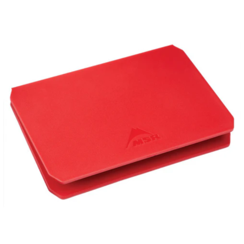 La tabla de cortar rectangular roja con diseño plegable presenta el logotipo de MSR y está inspirada en la portabilidad de la Base Estabilizadora MSR Trillium para Cocinillas (copia). Tiene bordes ligeramente redondeados y es compacta, perfecta para usar al aire libre o para acampar.