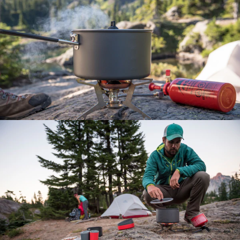 Una persona con ropa de exterior instala una estufa Cocinilla MSR WhisperLite Universal en un terreno rocoso. Una olla se calienta en la estufa, con el bote de combustible cerca. Se ven tiendas de campaña y montañas pintorescas al fondo, rodeadas de árboles.