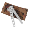 Un cascanueces plateado con múltiples agujeros en sus mangos reposa sobre una tela marrón doblada que presenta un patrón ornamentado en negro y rojo, que recuerda los intrincados diseños de la Cuchara MSR Alpine Tool Spoon (copia).