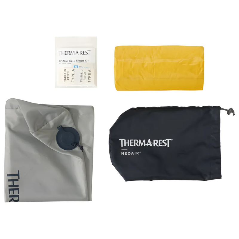 Imagen que muestra una colchoneta inflable amarilla Therm-a-Rest NeoAir XLite NXT, un kit de reparación gris y una bolsa de transporte negra, todos con el logotipo "Therm-a-Rest", cuidadosamente dispuestos sobre un fondo blanco.