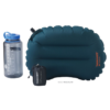 Una almohada inflable azul "Therm-a-Rest" en "tamaño regular" se encuentra junto a una botella de agua transparente con tapa azul y una bolsa negra. Este equipo listo para la aventura incluye el kit de reparación instantánea de campo Therm-a-Rest.