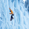 Ataviado con una chaqueta naranja y ropa de invierno, un escalador en una cascada helada usando piolets y crampones Grivel. Sujetos con gruesas cuerdas, confían en el Arnés Grivel Himani (copia) para mantener el equilibrio. Rodeados de grandes carámbanos, los árboles nevados forman un majestuoso telón de fondo invernal.