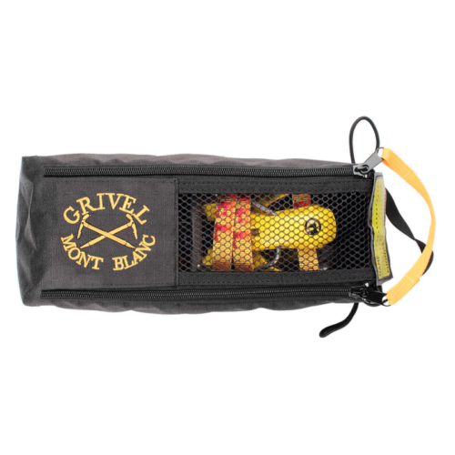 La bolsa para crampones Grivel Crampon Safe es una bolsa rectangular negra que presenta el logotipo "Grivel Mont Blanc" y el diseño de un piolet. Una ventana de malla revela el equipo de plástico amarillo y rojo en el interior y tiene una correa de transporte amarilla en un extremo.