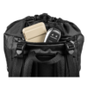 Una mochila Grivel Spartan 30, con correas de hombro acolchadas y un asa superior, muestra un dispositivo electrónico beige en su bolsillo superior con cremallera abierto y un llavero negro con botones de bloqueo/desbloqueo, ideal para aventuras en la montaña.