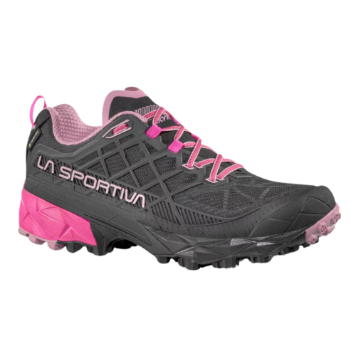 La zapatilla de montaña La Sportiva Akyra II GTX (copia) presenta un diseño geométrico en negro y rosa, una suela gruesa y bandas de rodadura prominentes para un mejor agarre. La palabra "La Sportiva" en el lateral enfatiza la durabilidad y el rendimiento en terrenos irregulares.