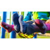 Los niños que llevan calcetines coloridos Calcetín Teko Hiking 3994 Merino XC Midweight Niños en azul, rosa y morado, combinados con botas rojas y chaquetas verdes y azules, juegan alegremente en el soleado patio de recreo.