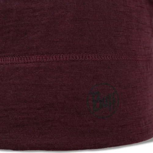 Un primer plano de una tela marrón con una línea de costura horizontal muestra la artesanía del Gorro Buff Lightweight Beanie, que presenta un sutil logotipo circular con "Buff" en la esquina inferior derecha.
