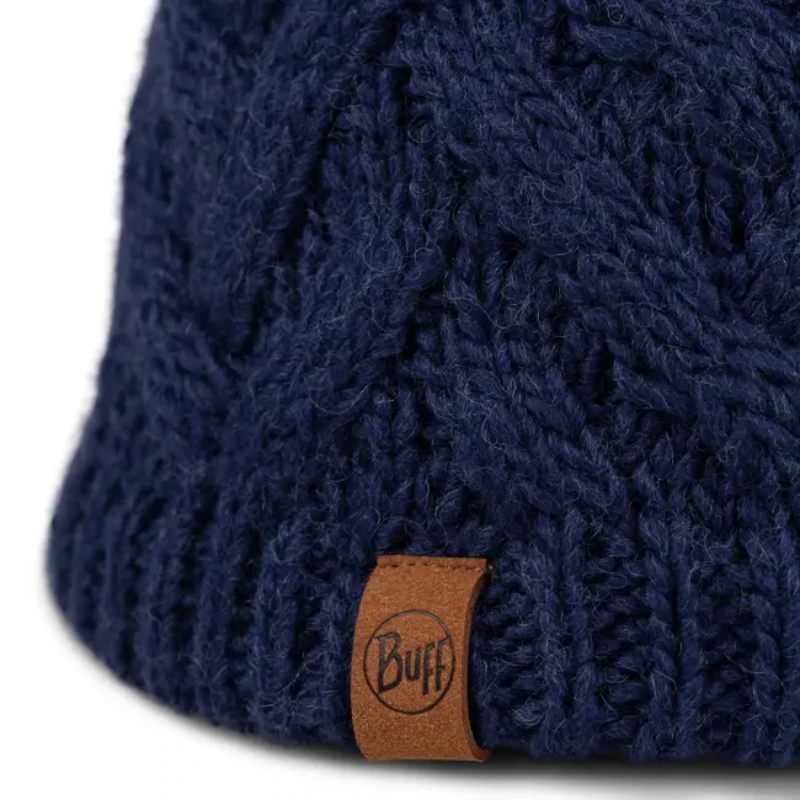 Primer plano de un gorro Buff Knitted y Polar Blein (copia) en azul oscuro con un patrón texturizado y una pequeña etiqueta de cuero marrón "Buff" en el borde inferior.