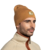 Una persona que viste un Gorro Buff Knitted Beanie Lilon Long y una chaqueta polar de color claro con cremallera se encuentra frente a un fondo blanco liso, con vello facial corto mientras mira hacia un lado.