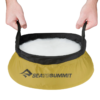Las manos sostienen suavemente una palangana redonda y plegable con fondo amarillo y borde negro, que rebosa de espuma de jabón blanca. Este diseño de Sea to Summit es tan práctico y versátil como la pala plegable Sea to Summit Nylon 66 Pocket Trowel para cada aventura.