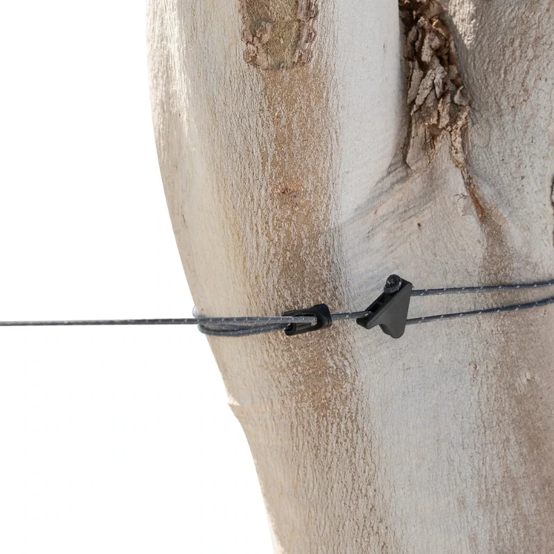 Un tronco de árbol está asegurado con un cable negro y una pequeña abrazadera negra, su corteza marrón claro texturizada contrasta con el fondo blanco. Cerca de allí, el Tendedero Portátil The Clothesline de Sea to Summit agrega una funcionalidad resistente a la escena.