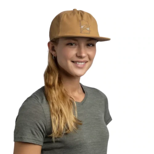 Una persona con una gorra vaquera Jockey Buff Niños Baseball Arrows y una camiseta gris sonríe a la cámara. Lleva el pelo largo y castaño claro recogido hacia un lado y lo complementa un pequeño aro. Un fondo blanco liso resalta su expresión alegre.